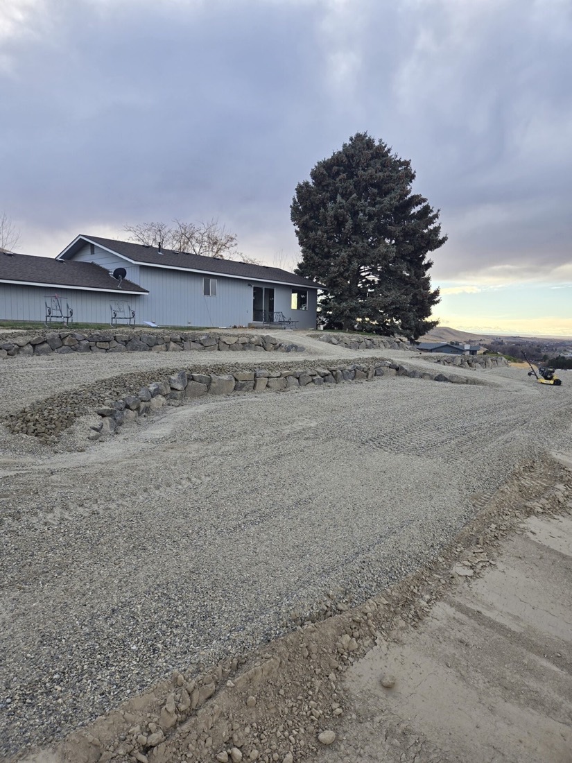 Graded and cleared building pad with rock retaining walls at a Yakima Valley home site